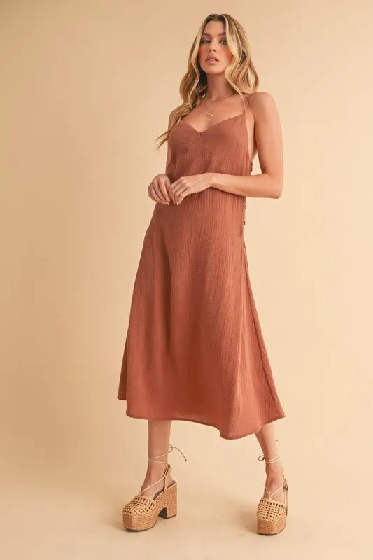 Woman wearing a midi cami dress with side buttons, made from 100% cotton, perfect for summer or casual wear.