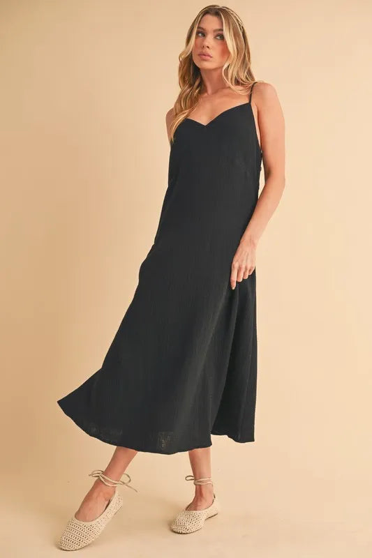 Woman wearing a midi cami dress with side buttons, made from 100% cotton, perfect for summer or casual wear.