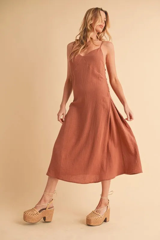 Woman wearing a midi cami dress with side buttons, made from 100% cotton, perfect for summer or casual wear.