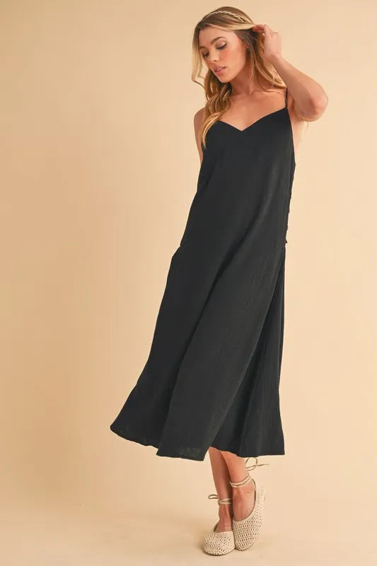 Woman wearing a midi cami dress with side buttons, made from 100% cotton, perfect for summer or casual wear.