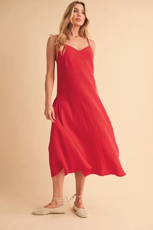 Woman wearing a midi cami dress with side buttons, made from 100% cotton, perfect for summer or casual wear.