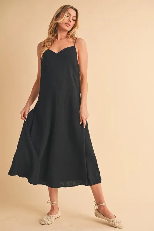 Woman wearing a midi cami dress with side buttons, made from 100% cotton, perfect for summer or casual wear.